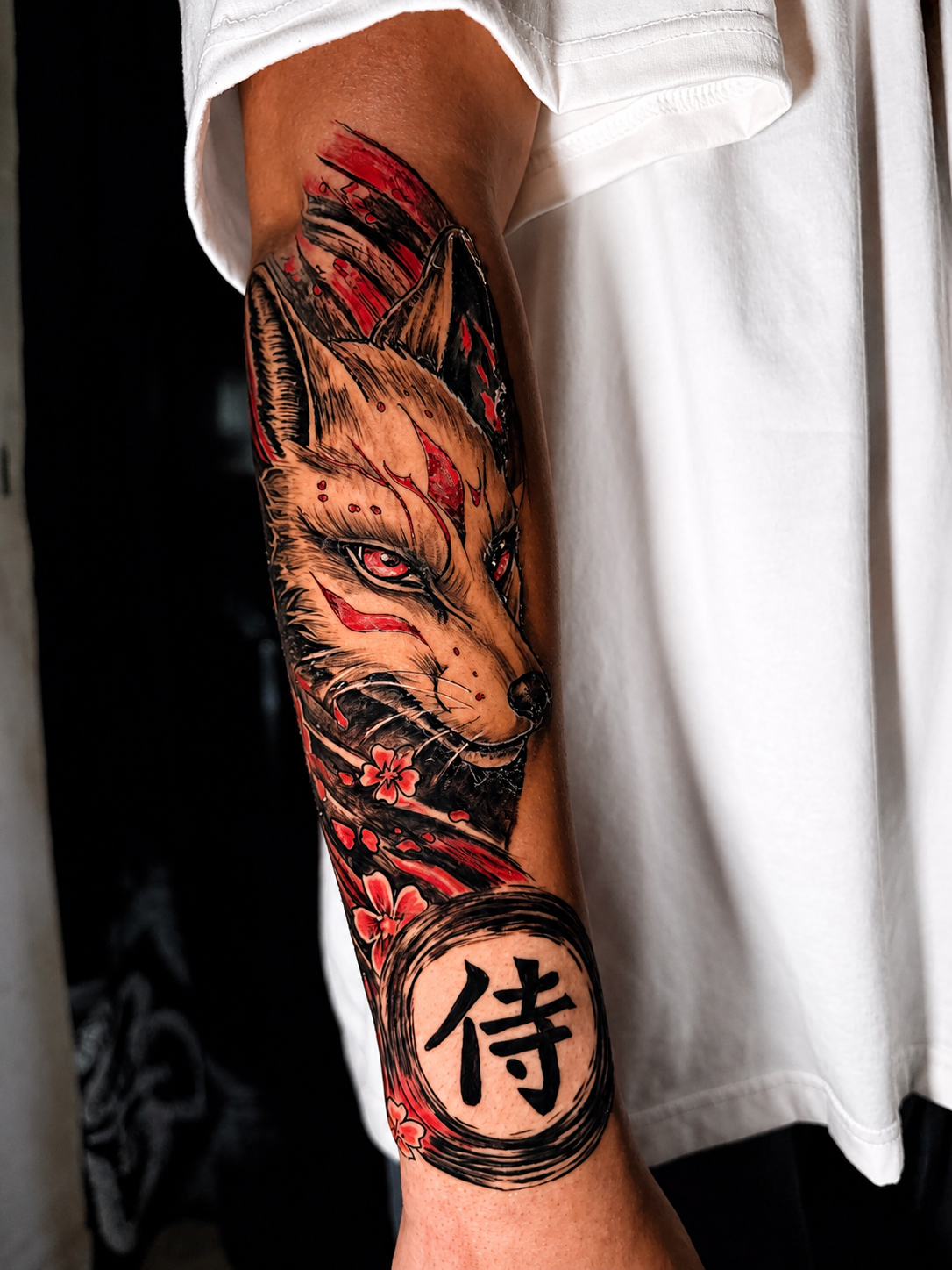 Tatuaje en antebrazo de kitsune japonés en black, grey y rojo realizado por Santana Art