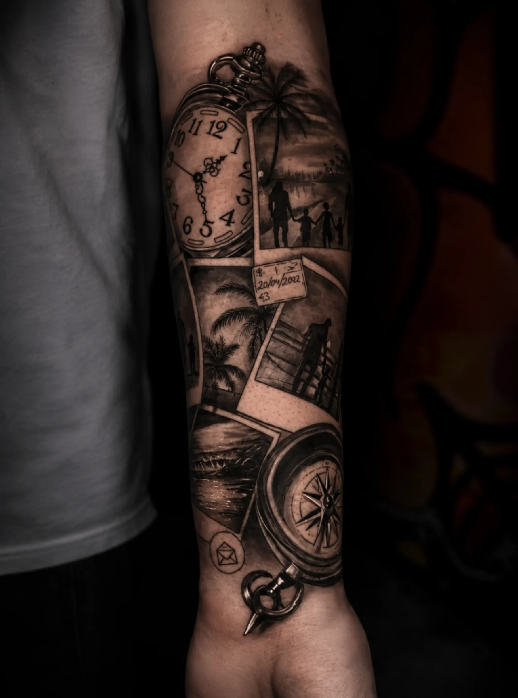 Tatuaje black and grey de reloj, palmeras y brújula realizado por Santana Art