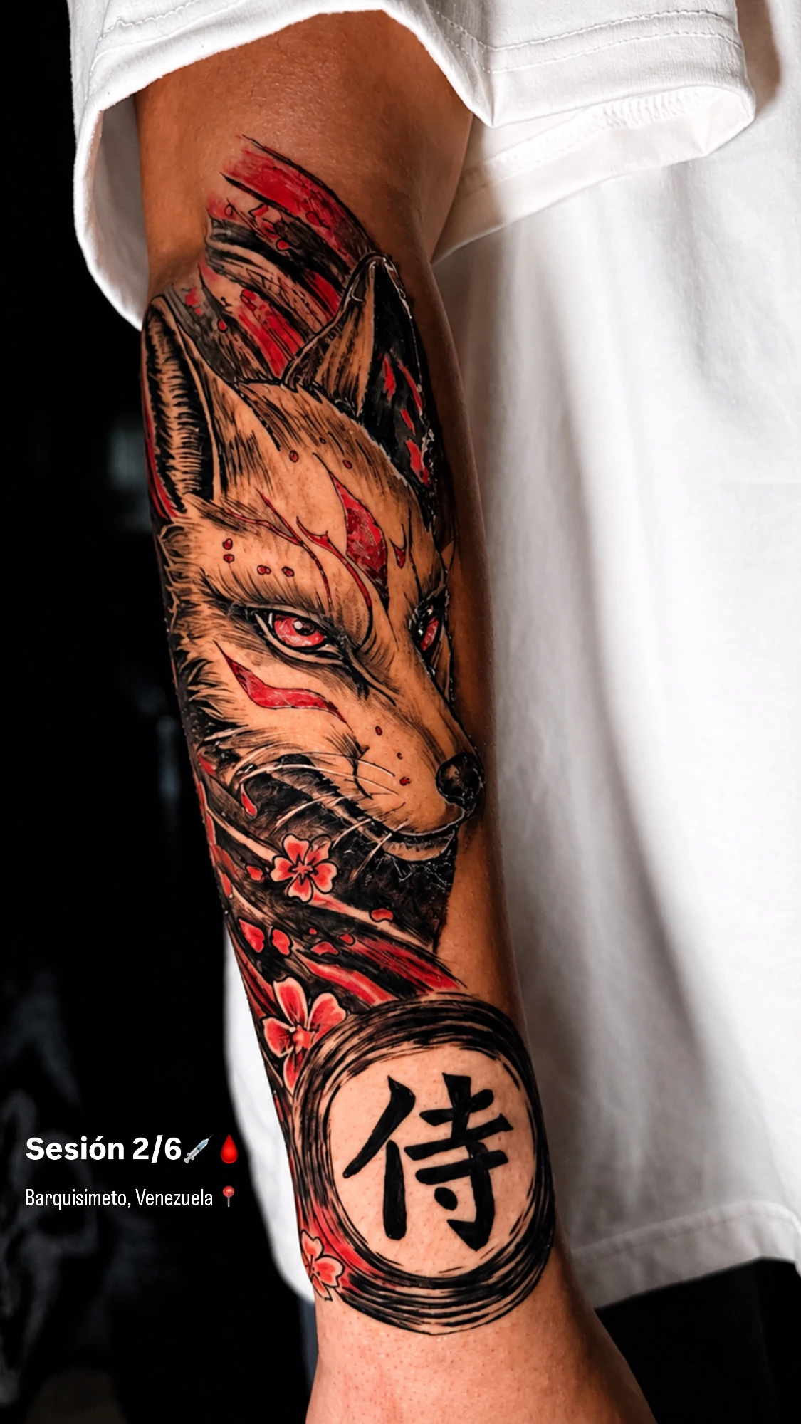 Tatuaje en antebrazo de kitsune japonés en black, grey y rojo realizado por Santana Art